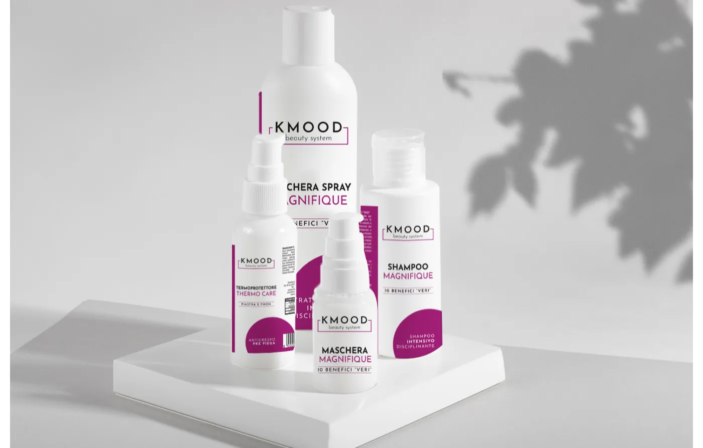 Quattro flaconi bianchi Kmood per capelli: maschera spray, shampoo, termoprotettore e maschera Magnifique