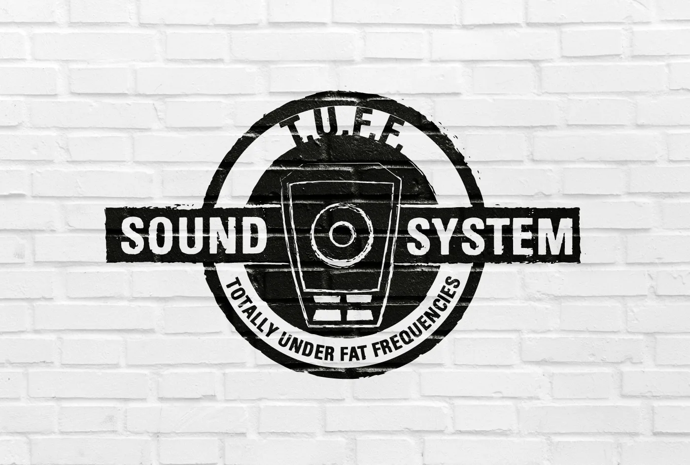 Logo T.U.F.F. Sound System, Totally Under Fat Frequencies, in nero su un muro di mattoni bianchi